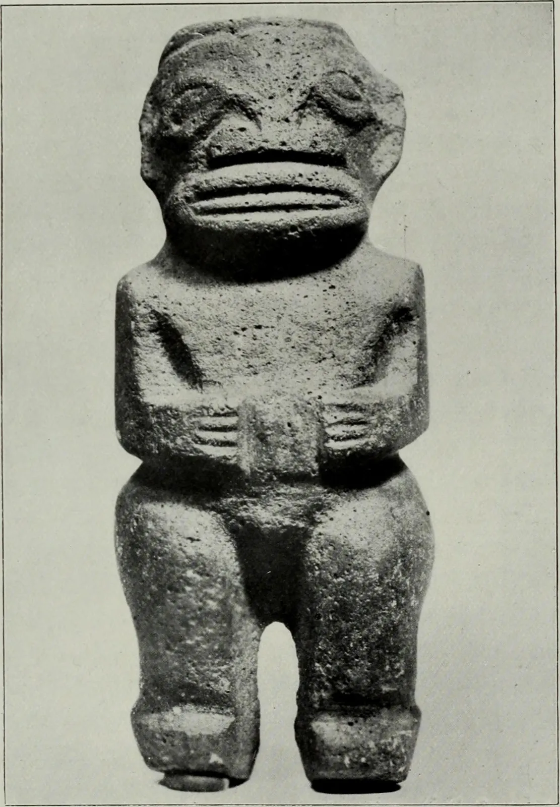 Historical photograph of a basalt tiki from Atuona, Hiva Oa, with large eyes, bent knees, and both hands spread across the abdomen.