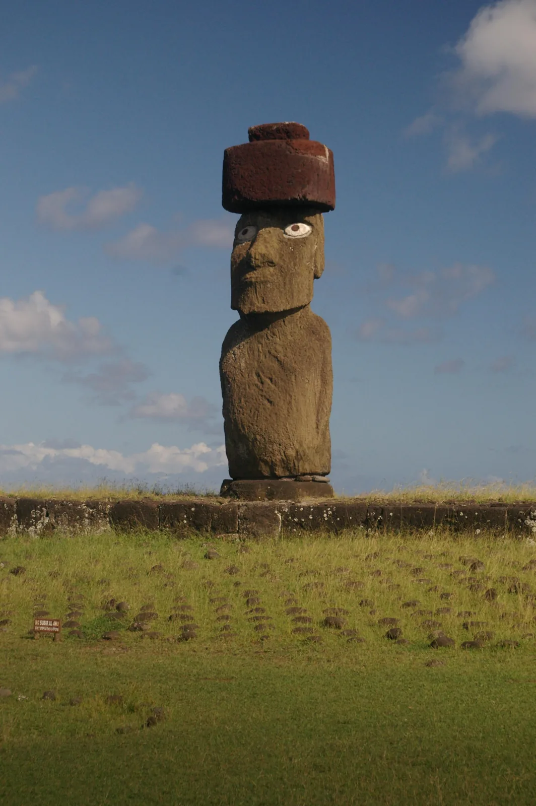 Ko te Riku moai at Tahai on Rapa Nui, standing on an ahu with reconstructed eyes and hands visible at the base of its torso.